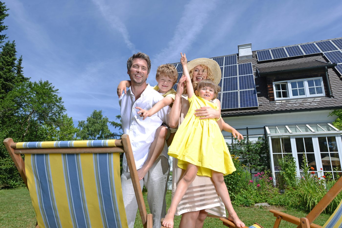 Familie im Garten vor einem Haus mit Photovoltaikanlage